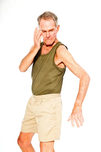 Atlético de buen aspecto hombre mayor verano casual vestido contra la pared blanca. Ejercitando sus músculos. Feliz, divertido y característico. Aislado. Captura de estudio . —  Fotos de Stock