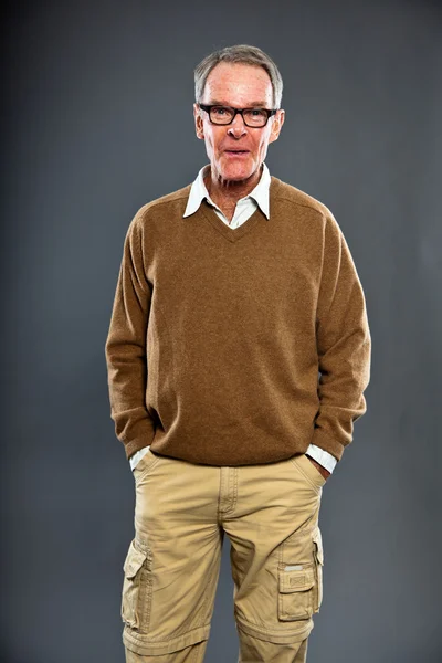 Expresivní dobře vypadající starší muž nosí brýle proti šedé zdi. zábavný a charakteristické. dobře oblečený. Studio záběr. — Stock fotografie