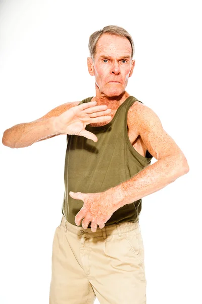 Athletisch gut aussehender älterer Herr lässig sommerlich gekleidet vor weißer Wand. Er trainiert seine Muskeln. glücklich, lustig und charakteristisch. Vereinzelt. Studioaufnahme. — Stockfoto