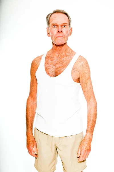 Ausdrucksstarker gut aussehender älterer Herr, lässig sommerlich gekleidet vor weißer Wand. glücklich, lustig und charakteristisch. Vereinzelt. Studioaufnahme. — Stockfoto