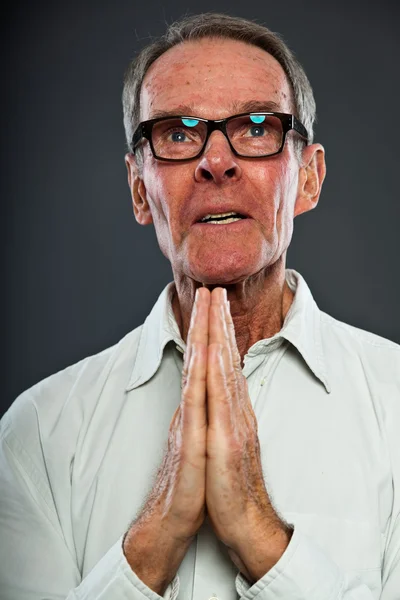 Hombre mayor expresivo y bien parecido con gafas contra la pared gris. Manos rezando. Espiritual y característico. Bien vestido. Captura de estudio . —  Fotos de Stock