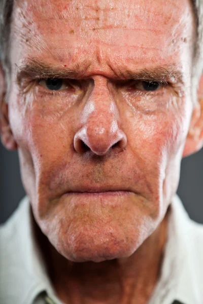 Close-up van expressieve goed uitziende senior man tegen grijs muur. grappig en karakteristiek. goed gekleed. studio opname. — Stockfoto