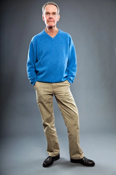 表現力豊かな良い灰色の壁に対してシニア男性を探しています。面白いと特性。よく服を着てください。青いセーター。スタジオ撮影. — ストック写真