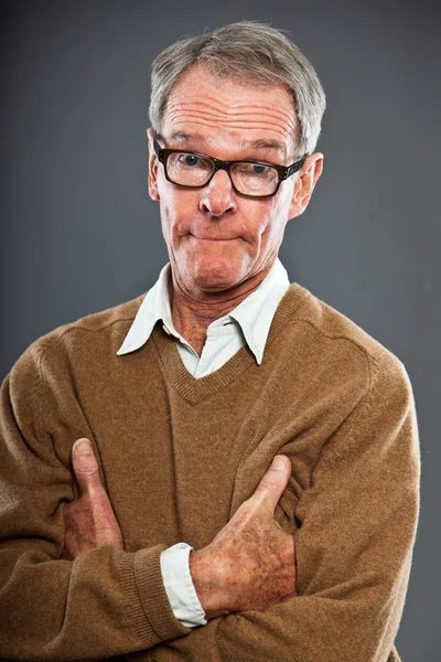 Ausdrucksstarker gut aussehender älterer Herr mit Brille vor grauer Wand. Witzig und charakteristisch. Gut angezogen. Studioaufnahme. — Stockfoto