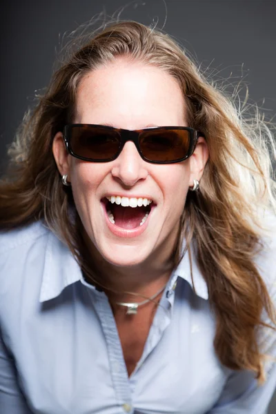 Pretty woman long blond hair wearing sunglasses and light blue shirt. Isolated on grey background. Studio shot. — Stock Photo, Image