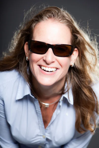 Mujer bonita pelo largo y rubio con gafas de sol y camisa azul claro. Aislado sobre fondo gris. Captura de estudio . — Foto de Stock