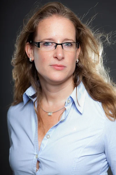 Hübsche Frau mit langen blonden Haaren, Brille und hellblauem Hemd. isoliert auf grauem Hintergrund. Studioaufnahme. — Stockfoto