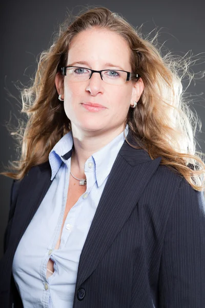 Bella donna d'affari lunghi capelli biondi con occhiali e vestito blu. Isolato su sfondo grigio. Studio girato . — Foto Stock