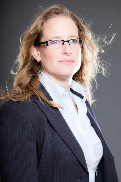 Mulher de negócios bonita cabelo loiro longo usando óculos e terno azul. Isolado sobre fundo cinzento. Estúdio . — Fotografia de Stock