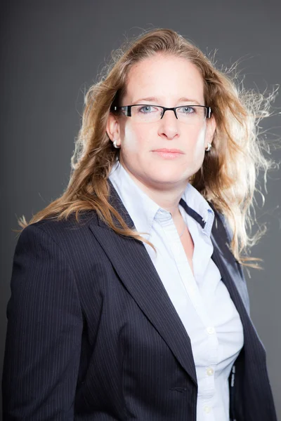 Pretty business woman long blond hair wearing glasses and blue suit. Isolated on grey background. Studio shot. — Stock Photo, Image