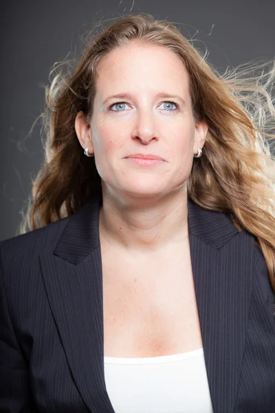 Hübsche Geschäftsfrau mit langen blonden Haaren und blauem Anzug. isoliert auf grauem Hintergrund. Studioaufnahme. — Stockfoto