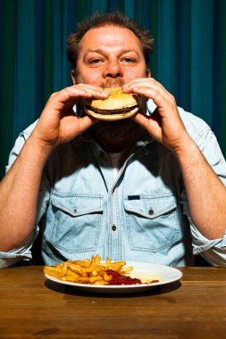 fast food yemek yeme sakallı adam. hamburger ve patates kızartması zevk.