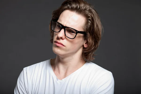 Joven guapo con pelo largo marrón y gafas retro aisladas sobre fondo gris. Estudio de moda filmado. Cara expresiva . —  Fotos de Stock