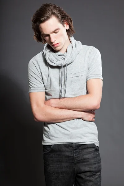 Красивий молодий чоловік з коричневим довгим волоссям у сірій сорочці ізольований на сірому фоні. Студійний знімок моди. Експресивне обличчя . — стокове фото