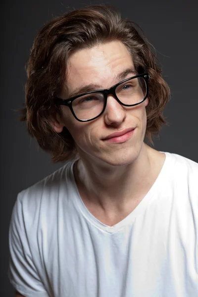 Handsome young man with brown long hair and retro glasses isolated on grey background. Fashion studio shot. Expressive face. — Stock Photo, Image