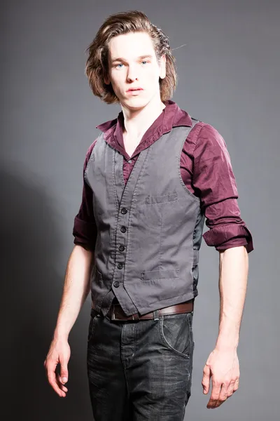 Handsome young man with brown long hair isolated on grey background. Fashion studio shot. Expressive face. — Stock Photo, Image