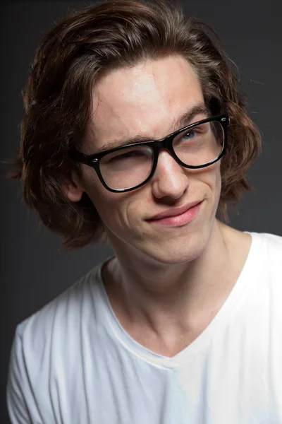 Όμορφος νεαρός άνδρας με καστανά μακριά μαλλιά και ρετρό γυαλιά που απομονώνονται σε γκρι φόντο. στούντιο μόδας πυροβόλησε. εκφραστικό πρόσωπο. — Φωτογραφία Αρχείου