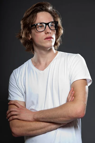 Przystojny, młody człowiek z brązowe długie włosy i okulary retro na białym tle na szarym tle. strzał studio mody. — Zdjęcie stockowe