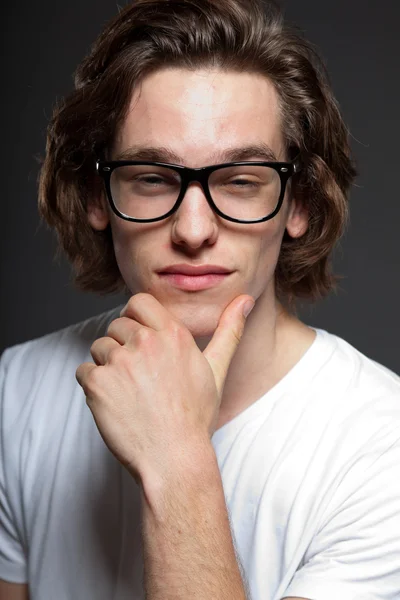 Joven guapo con pelo largo marrón y gafas retro aisladas sobre fondo gris. Estudio de moda filmado. Cara expresiva . — Foto de Stock