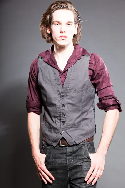 Handsome young man with brown long hair isolated on grey background. Fashion studio shot. Expressive face. — Stock Photo, Image