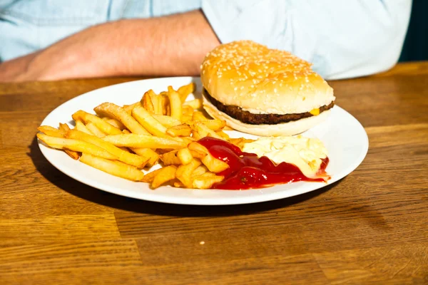 Junk food on wooden table. Fast food. French fries and hamburger with mayonaise and ketchup. — Stock Photo, Image