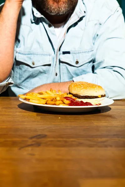 La malbouffe sur la table en bois. Restauration rapide. Frites et hamburger à la mayonnaise et au ketchup . — Photo