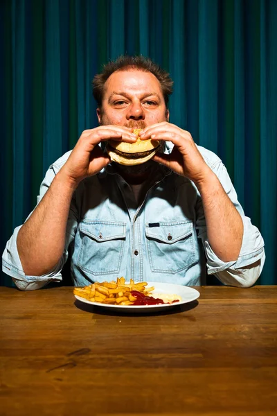 Man with beard eating fast food meal. Enjoying french fries and a hamburger. — Stock Photo, Image