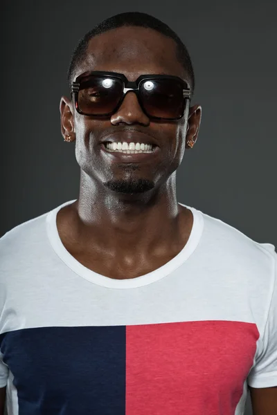 Cool urban stylish black american man. Fashion studio portrait isolated on grey background. Wearing dark sunglasses. Smiling. — Stock Photo, Image