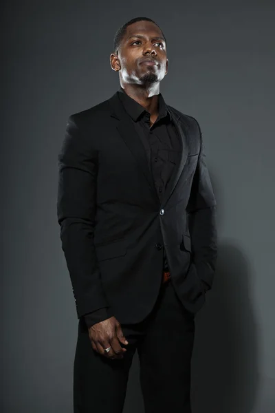 Cool американський чоловік у чорному темному костюмі. студії моди вистрілив ізольовані на сірий фон. — стокове фото