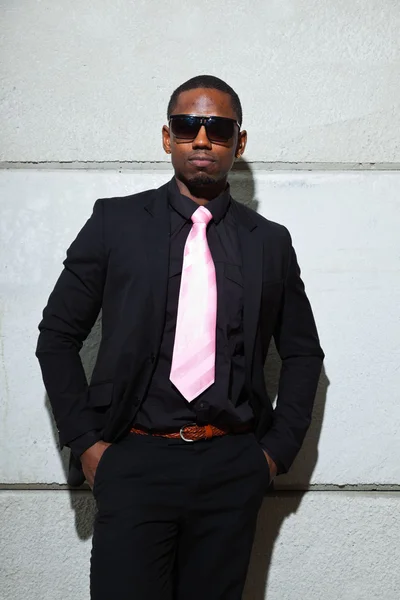 Cooler schwarzer amerikanischer Mann im dunklen Anzug mit Sonnenbrille. Modenschau im urbanen Umfeld. — Stockfoto