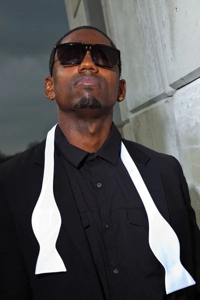 Cooler schwarzer amerikanischer Mann im dunklen Anzug mit Sonnenbrille. Modenschau im urbanen Umfeld. — Stockfoto