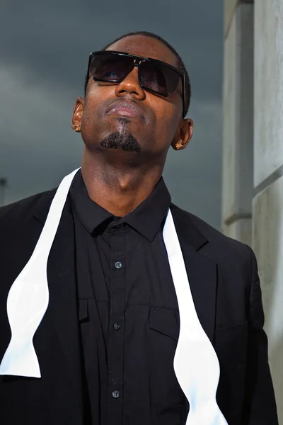 Cool svart amerikansk man i mörk kostym bär solglasögon. mode skott i urban miljö. — Stockfoto