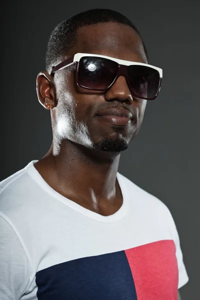 Cool urbano elegante hombre negro americano. Retrato de estudio de moda aislado sobre fondo gris. Usar gafas de sol oscuras . — Foto de Stock