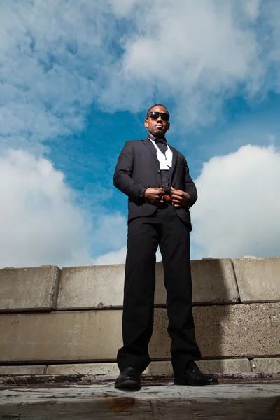 Cool homme noir américain en costume sombre portant des lunettes de soleil. Mode prise en milieu urbain. Ciel nuageux bleu . — Photo