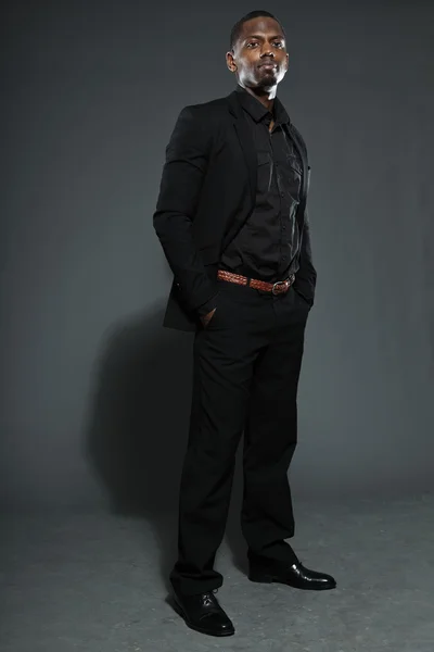 Hűvös, fekete amerikai férfi sötét öltöny. Stúdió divat lövés elszigetelt a szürke háttér. — Stock Fotó
