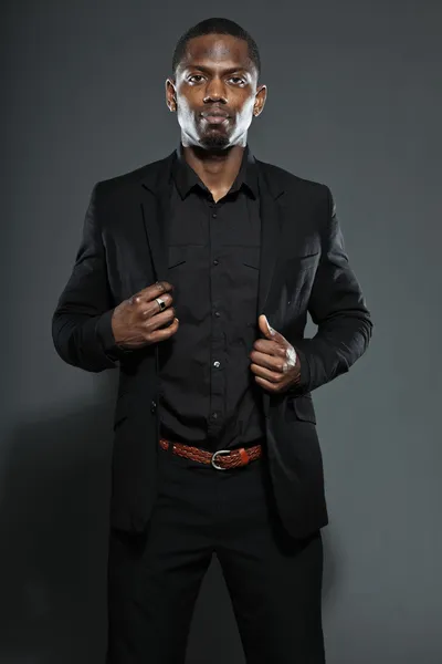 Hűvös, fekete amerikai férfi sötét öltöny. Stúdió divat lövés elszigetelt a szürke háttér. — Stock Fotó
