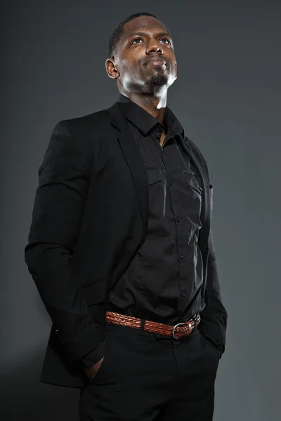 Freddo uomo nero americano in abito scuro. Studio moda girato isolato su sfondo grigio . — Foto Stock