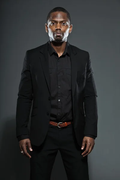 Cool svart amerikansk man i mörk kostym. Studio mode skott isolerade på grå bakgrund. — Stockfoto