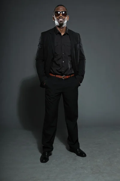 Cooler schwarzer amerikanischer Mann im dunklen Anzug. Studiomode, isoliert auf grauem Hintergrund aufgenommen. mit dunkler Sonnenbrille. — Stockfoto
