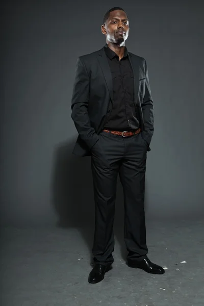 Cool zwarte Amerikaanse man in donker pak. Studio mode schot geïsoleerd op grijze achtergrond. — Stockfoto