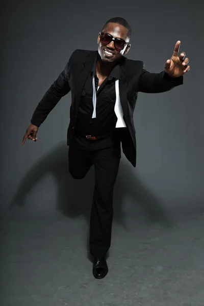 Hűvös, fekete amerikai férfi sötét öltöny. divat stúdió lövés elszigetelt a szürke háttér. sötét napszemüveget visel. — Stock Fotó