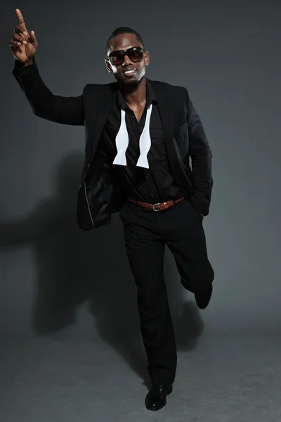 Cool svart amerikansk man i mörk kostym. Studio mode skott isolerade på grå bakgrund. bär mörka solglasögon. — Stockfoto