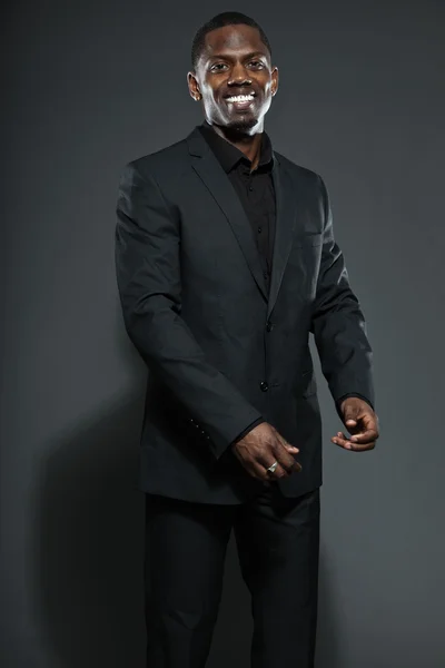 Um americano negro fixe de fato escuro. Estúdio moda tiro isolado no fundo cinza . — Fotografia de Stock