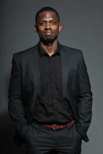 Cool svart amerikansk man i mörk kostym. Studio mode skott isolerade på grå bakgrund. — Stockfoto