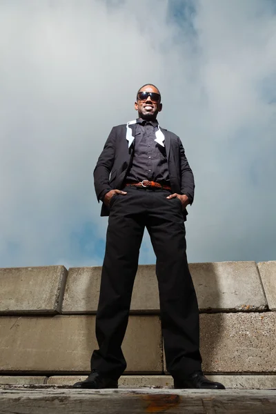 Cool zwarte Amerikaanse man in donker pak dragen van een zonnebril. mode schot in stedelijke omgeving. — Stockfoto