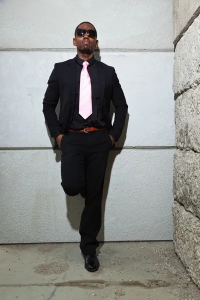 Freddo uomo nero americano in abito scuro con gli occhiali da sole. Moda scattata in ambiente urbano . — Foto Stock