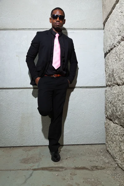Cool black american man in dark suit wearing sunglasses. Fashion shot in urban setting. Stock Photo