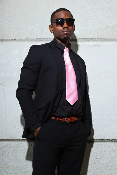 Cool black american man in dark suit wearing sunglasses. Fashion shot in urban setting. Stock Picture