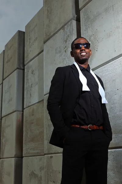 Cool black american man in dark suit wearing sunglasses. Fashion shot in urban setting. Stock Image