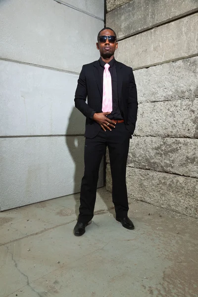 Cool black american man in dark suit wearing sunglasses. Fashion shot in urban setting. Royalty Free Stock Images
